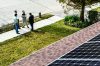 solar panels on a house roof with men discussing on the sidewalk