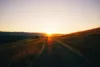 sunset on a road with fields to the side